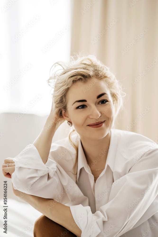 Portrait of a blond wavy-haired young confident and successful girl. Youth, lifestyle and happiness concept. A photo with a blurred background.