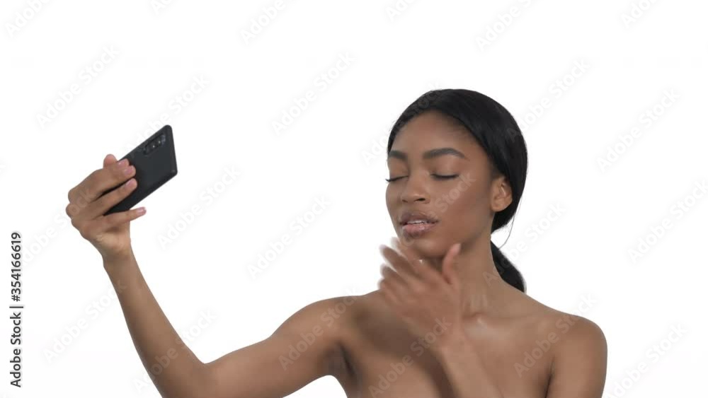 Close-up portrait of a charming African woman posing to camera, touching her face, making selfie. Isolated, on white background Close-up portrait of a charming African woman posing to camera, touching her face, making selfie. Isolated, on white background