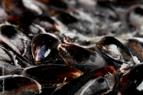 Fresh mussels with ice, seafood. Shellfish on a stone dark table, top view, macro