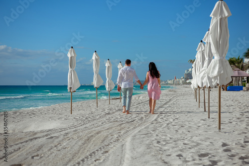 A man and a woman walk on the seashore and look at the horizon.