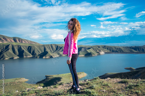 Beautiful young woman smiling at the camera with lake in the background © Vahagn