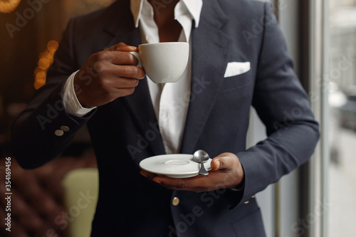 Black man in a cafe. Man in a black suit. Businessman drinking a coffee.