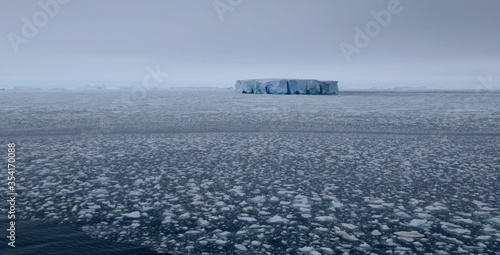 Edge of pack ice in antarctic ocean with large iceberg, Antarctica