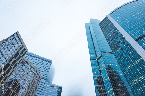 Skyscrapers of the office center made of glass and concrete in clouds of thick fog. © fifg