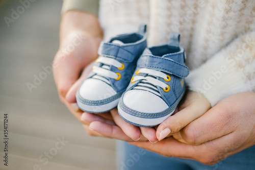 Closeup of a hands holding a pair of small blue baby shoes