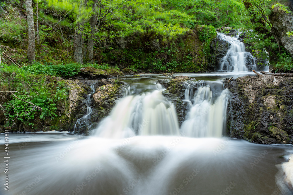 Stunning Slow falling Water Hallamolla Waterfall in lush rural Forest during springtime in Skane Osterlen near national park Stenshuvud, South Sweden.  Long Exposure Waterfall.