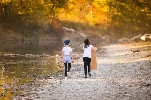 Two little girls playing on the riverside. Autumn in the yellow forest