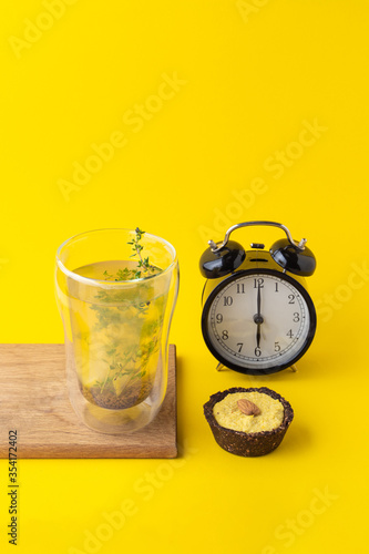 Conceptual food photo of healthy snacks on minimalist bright yellow background: vegan lemon pie and herbal tea