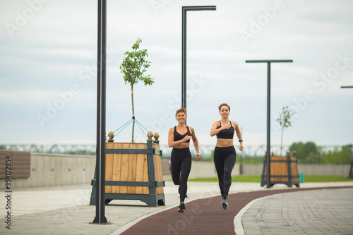 two beautiful adult women in sportswear jogging outdoors in summer © Alexandr