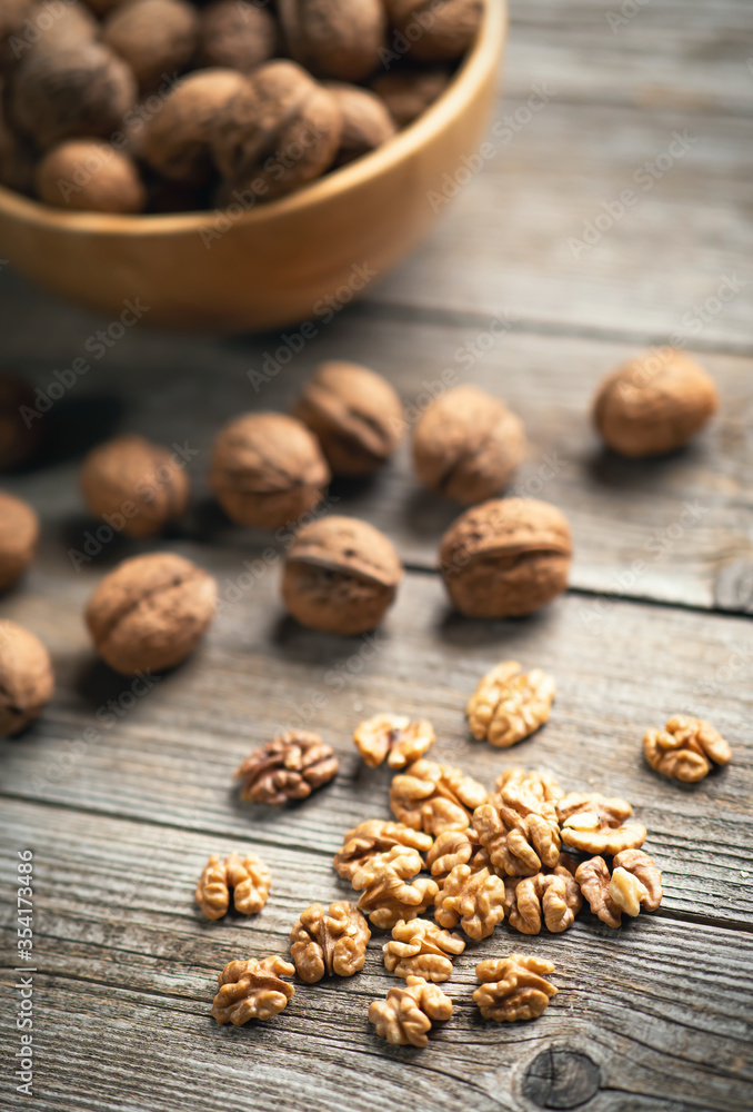 Fresh walnut kernels and whole walnuts in a bowl on rustic old wooden table. Healthy organic food, BIO viands, natural background. Copy space for your advertising text message Fresh walnut kernels and whole walnuts in a bowl on rustic old wooden table. Healthy organic food, BIO viands, natural background. Copy space for your advertising text message