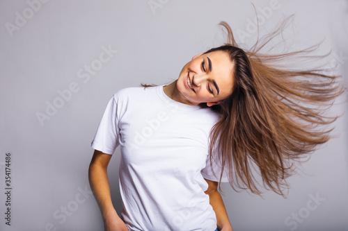young woman smiling and waving her hair in studio. close up. whi