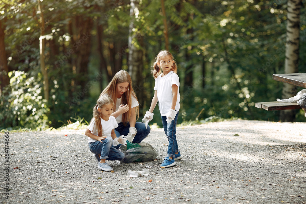 Fototapeta premium Volunteers collects rubbish. Children in a park. Kids in a white t-shirts