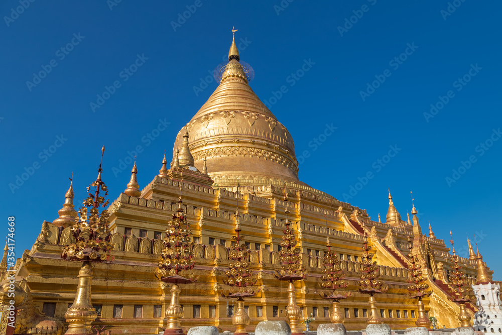 Naklejka premium Shwezigon pagoda is the only fully coated by gold bell shaped Buddhist stupa in Bagan, Myanmar, a prototype for all Burmese stupas. Shwezigon paya enshrines Buddha tooth and bone relics