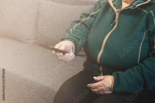 An elderly woman with a remote control, a grandmother and a remote control from the TV, a remote control in the hands of grandmother © vell