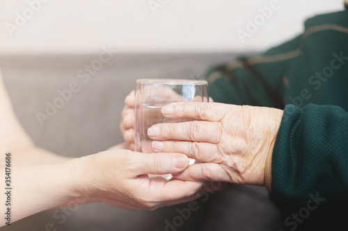 Grandmother with a glass of water, granddaughter gives grandmother a glass of water