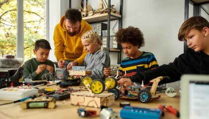 Focus on quality. Young technicians building a robot, working with a wiring kit together with a male teacher at a stem robotics class. Inventions and creativity for kids