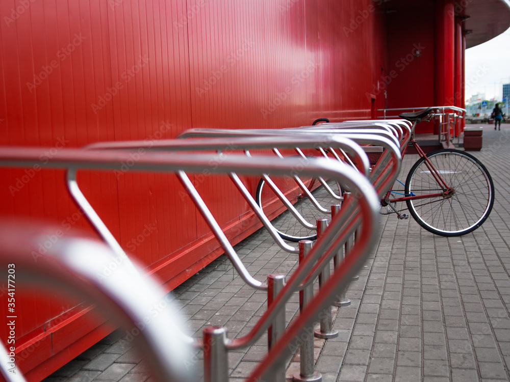Parking for bicycles. one bike is parked in the Parking lot. red background Parking for bicycles. one bike is parked in the Parking lot. red background