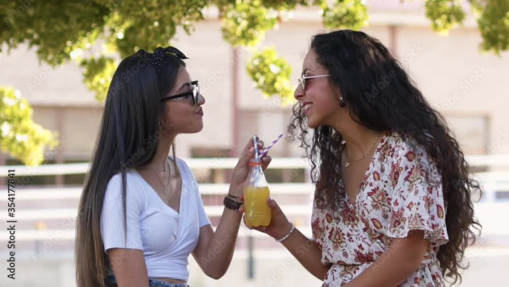 Hipster best friends sharing soda with paper straws and laughing Hipster best friends sharing soda with paper straws and laughing