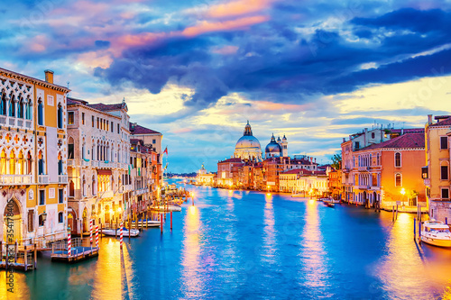 Basilica Santa Maria della Salute, Punta della Dogona and Grand Canal at blue hour sunset in Venice, Italy with boats and reflections.