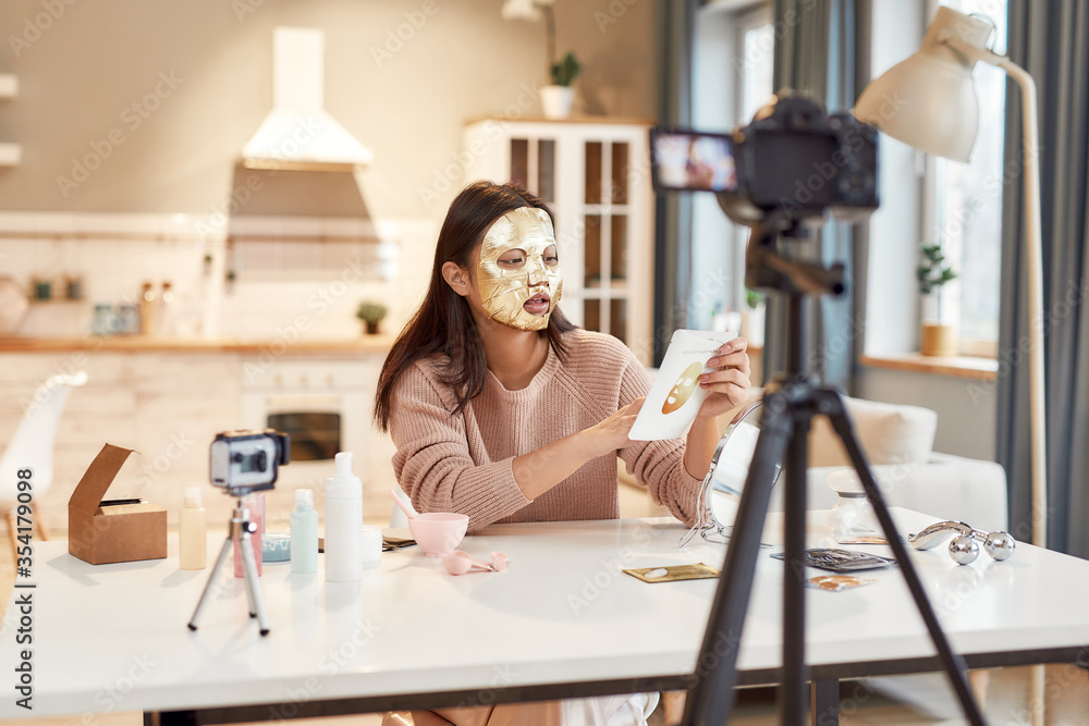 Wow your online audience. Young female blogger recording a tutorial video for her beauty blog about skincare routine. Vlogger testing face mask, recording video for social network Wow your online audience. Young female blogger recording a tutorial video for her beauty blog about skincare routine. Vlogger testing face mask, recording video for social network