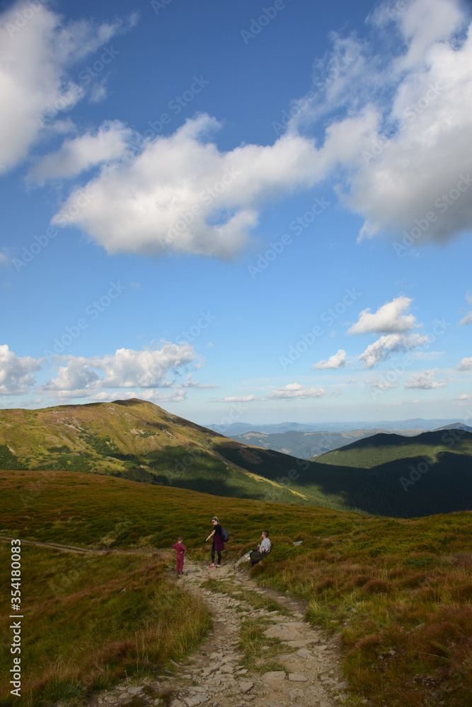 Several travelers walking along the ridge to the top of the mountain against the sky Several travelers walking along the ridge to the top of the mountain against the sky