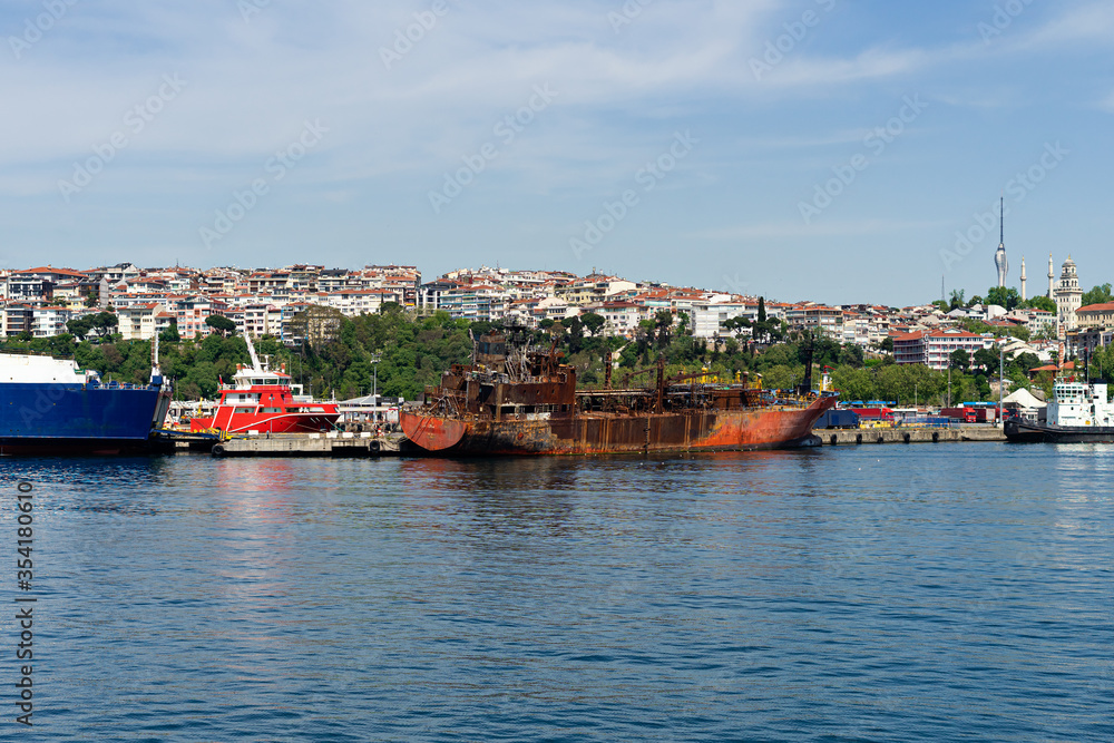 abandoned rusty ship near coastline in Istanbul city with unban cityscape background