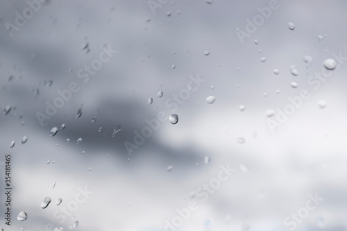 Water drops on glass window with dark clouds on background