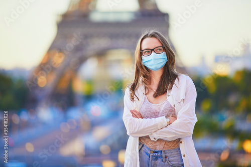 Young girl standing near the Eiffel tower in Paris and wearing protective face mask © Ekaterina Pokrovsky