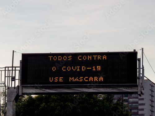 illuminated sign with warning phrase about Covid-19. Translation: All against Covid-19. use mascara.