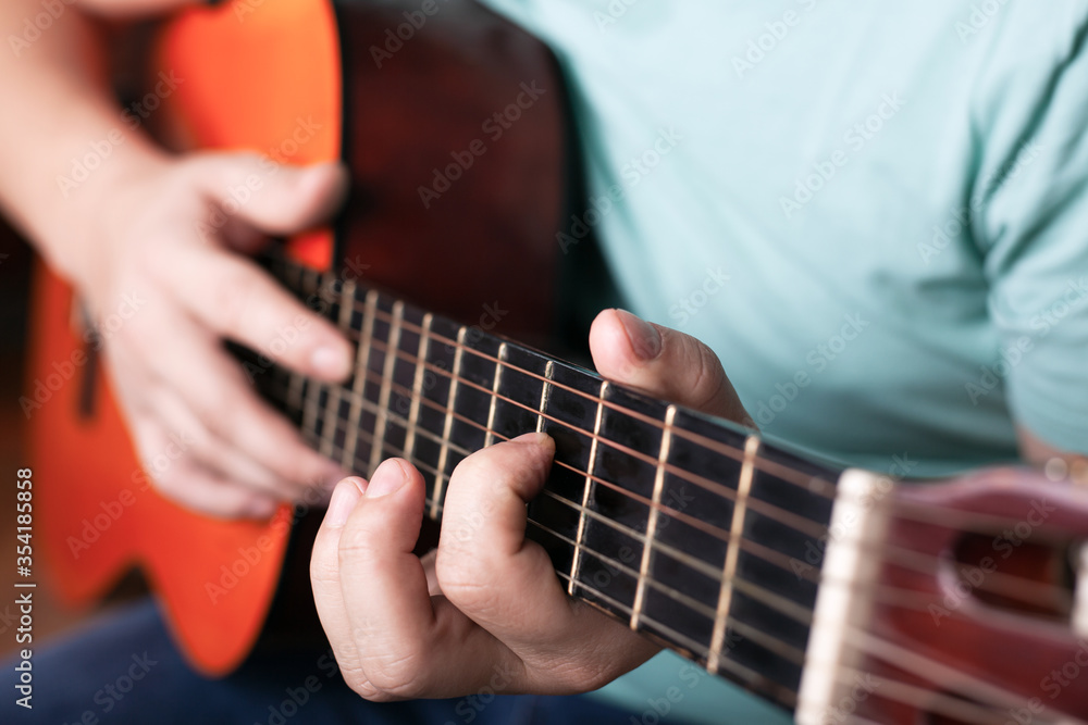 playing the acoustic guitar close-up, hand grips the chord, playing a musical instrument