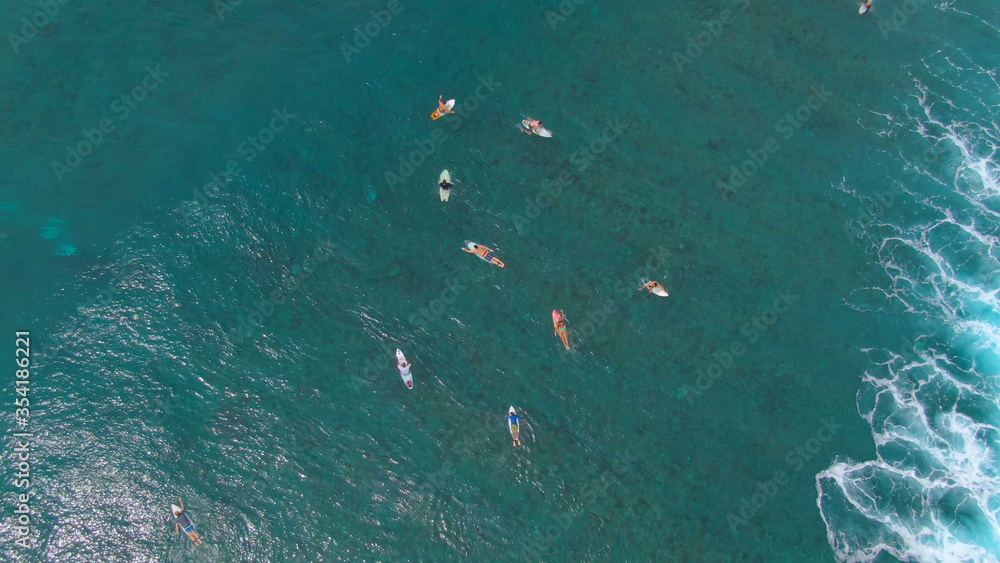 TOP DOWN: Group of friends on surfing trip in Maldives paddle out to the line up