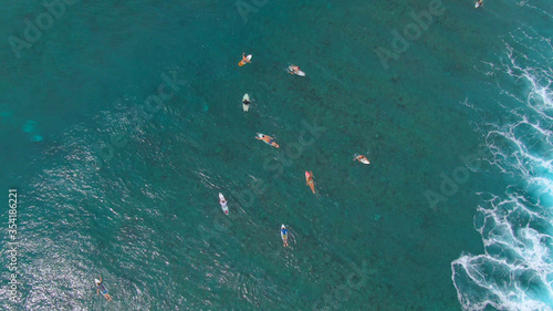 TOP DOWN: Group of friends on surfing trip in Maldives paddle out to the line up © helivideo