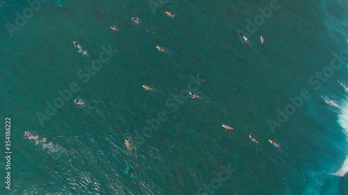 Photography TOP DOWN: Massive barrel wave crashes and splashes over surfers paddling out