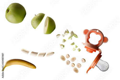 banana and apple slicing falling into the baby nibbler isolated white with copy space photo