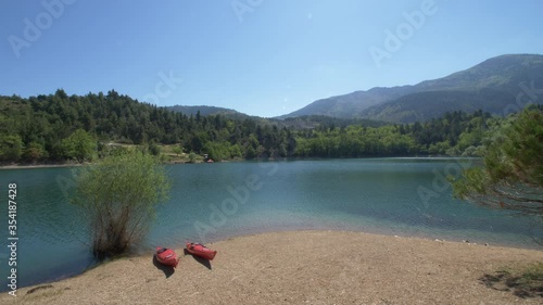 Slow drone shot of two red kayaks on beach at Lake Tsivlou, Greece photo