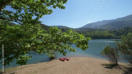 Slow aerial shot of two red canoes by shore of Tsivlou Lake, Greece photo