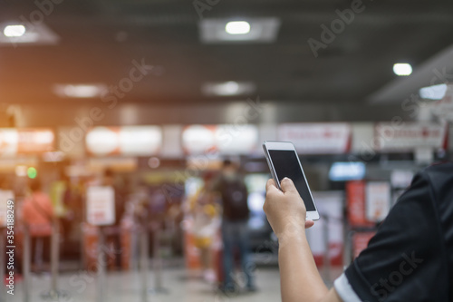 Checkin online or booking by Smartphone Concept: Hands using smart phone apps in airport forCheck in through mobile application, Traveler at airport departure lounge travel in airplane