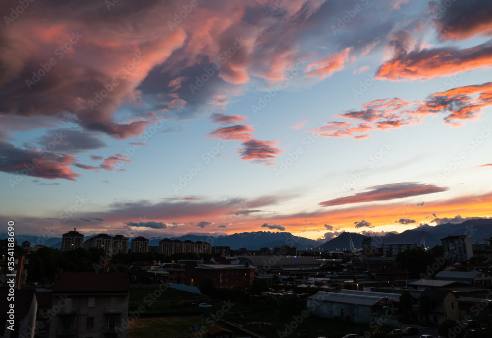 Turin,Piedmont,Italy. May 2020. In the northern suburbs of the city a breathtaking sunset with clouds in warm and bright colors.The mountains of the Alps are on the horizon. The pillars of the stadium