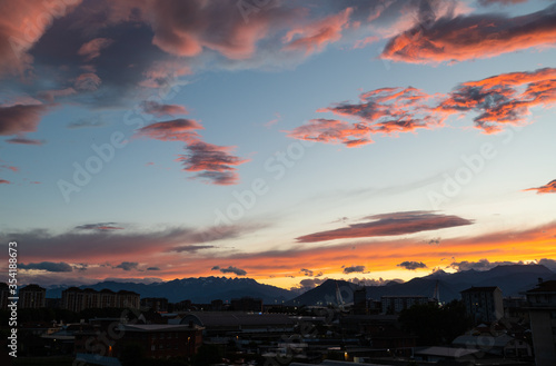 Turin,Piedmont,Italy. May 2020. In the northern suburbs of the city a breathtaking sunset with clouds in warm and bright colors.The mountains of the Alps are on the horizon. The pillars of the stadium