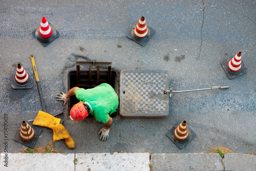 sequence of worker going in the manhole in the street, step 3