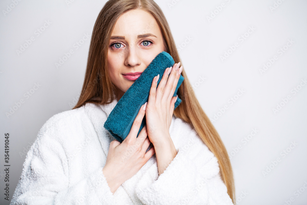 Face care, beautiful woman wipes her face with a towel after taking a shower