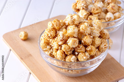 Sweet caramel popcorn in glass bowl. Close up. Light background. photo