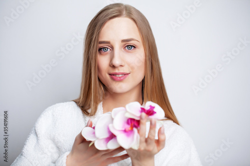 Facial care. Young woman with beautiful skin holds an orchid