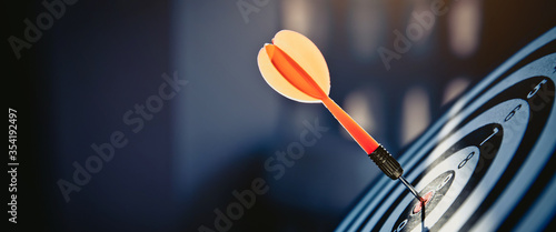 Bullseye or dart board has dart arrow throw hitting the center of a shooting target for business targeting and winning goals business concepts.