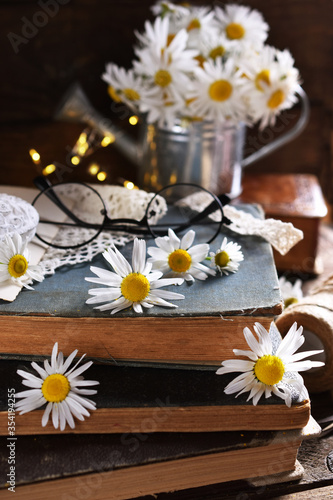 rustic style still life with old books and daisy flowers on wooden table