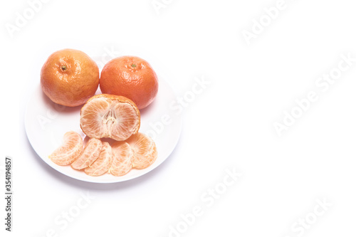 Whole  peeled tangerines on a white plate with space for text