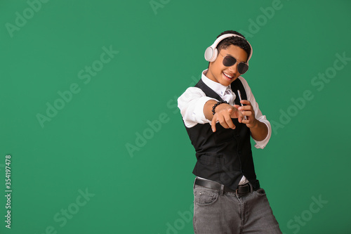 African-American teenager dancing and listening to music against color background