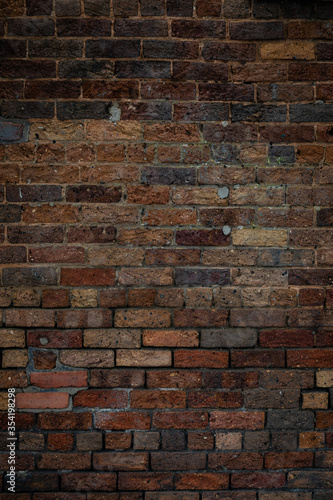 Dark brick wall texture featuring a variety of mixed bricks in many colors, backdrop for creative copy space, vertical aspect