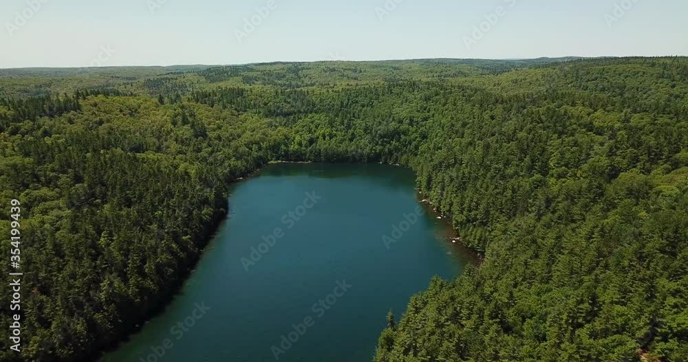 Giant Canadian lake seaside forest of Ompah, Ontario Highlands Of Canada. Drone aerial shot above Lake view mountain with green Cypress trees blue water at Canadian tourist adventure. Giant Canadian lake seaside forest of Ompah, Ontario Highlands Of Canada. Drone aerial shot above Lake view mountain with green Cypress trees blue water at Canadian tourist adventure.