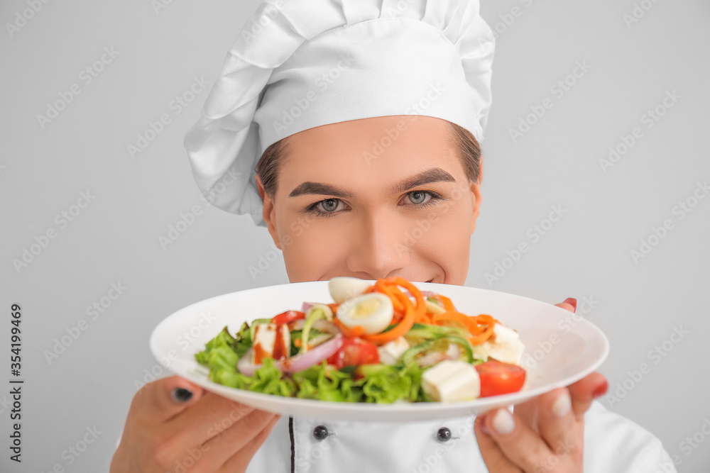 Transgender chef with salad on light background Transgender chef with salad on light background